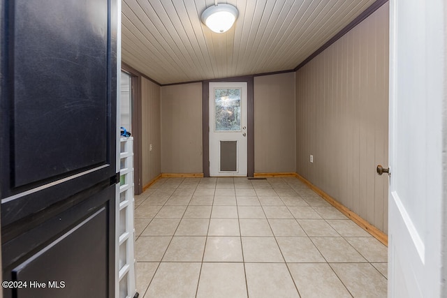 tiled entrance foyer featuring wood walls, lofted ceiling, ornamental molding, and wood ceiling