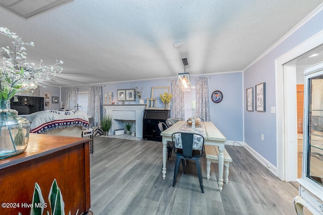 dining room featuring a textured ceiling, wood-type flooring, and crown molding