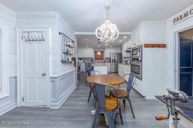 dining space with hardwood / wood-style flooring, ornamental molding, and an inviting chandelier