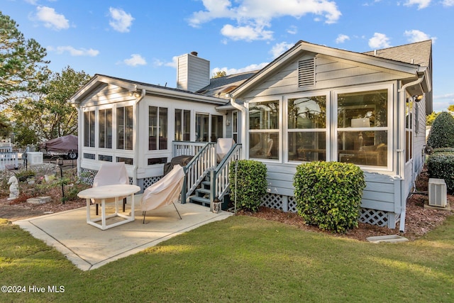 rear view of house with cooling unit, a yard, a patio area, and a sunroom