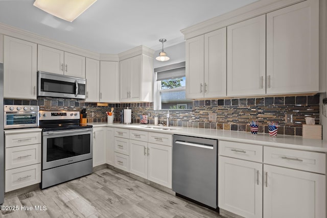 kitchen featuring appliances with stainless steel finishes, a sink, light countertops, and decorative backsplash