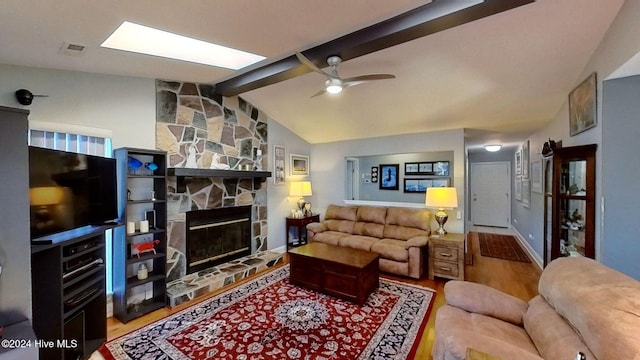 living room featuring ceiling fan, a stone fireplace, lofted ceiling with beams, and hardwood / wood-style floors