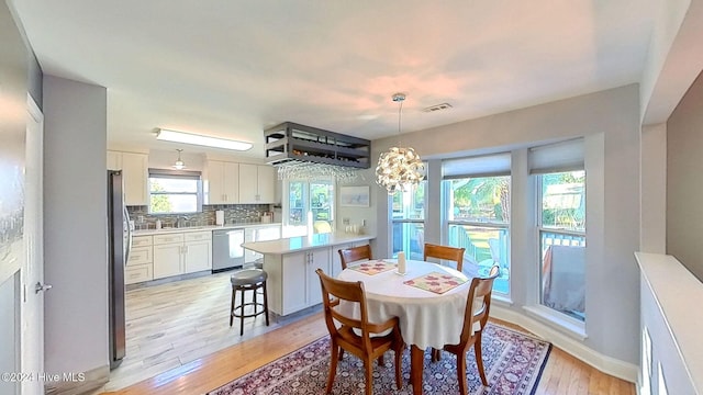 dining space featuring an inviting chandelier, sink, and light hardwood / wood-style floors