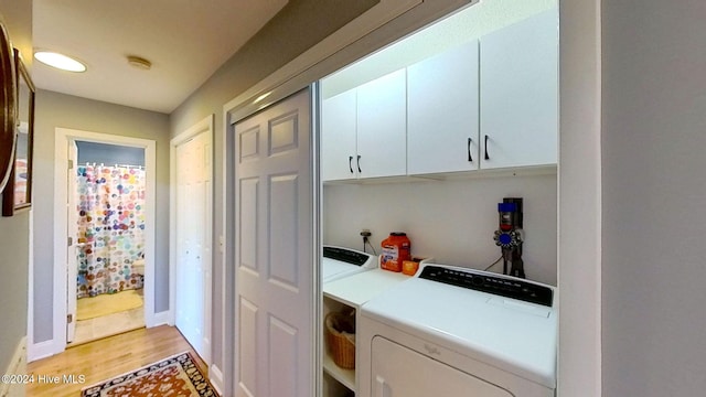 laundry area featuring cabinets, washing machine and dryer, and light wood-type flooring