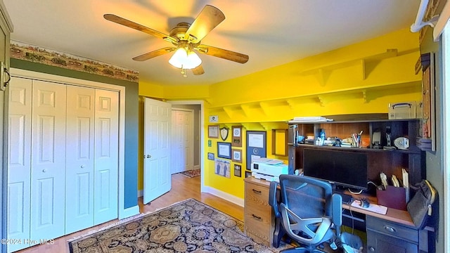 home office with light hardwood / wood-style flooring and ceiling fan