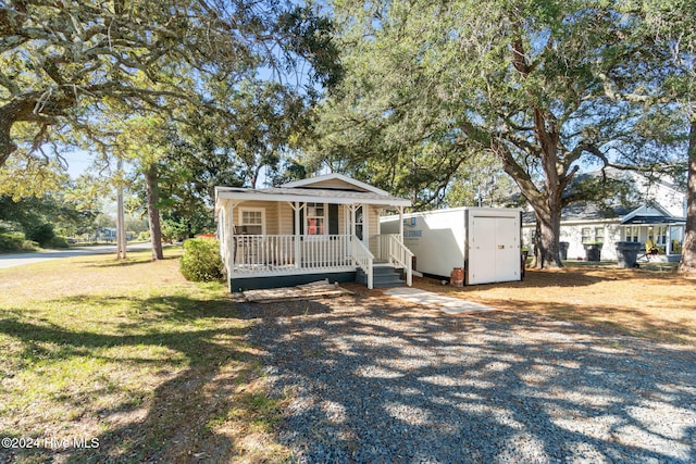 view of front of property with a porch, a storage shed, and a front lawn