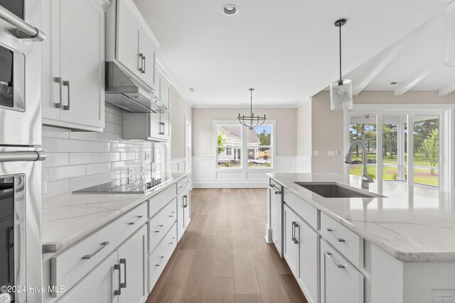 kitchen featuring dark hardwood / wood-style flooring, black electric cooktop, sink, a center island with sink, and white cabinets