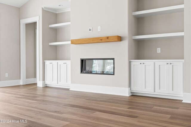 unfurnished living room featuring light wood-type flooring and built in features