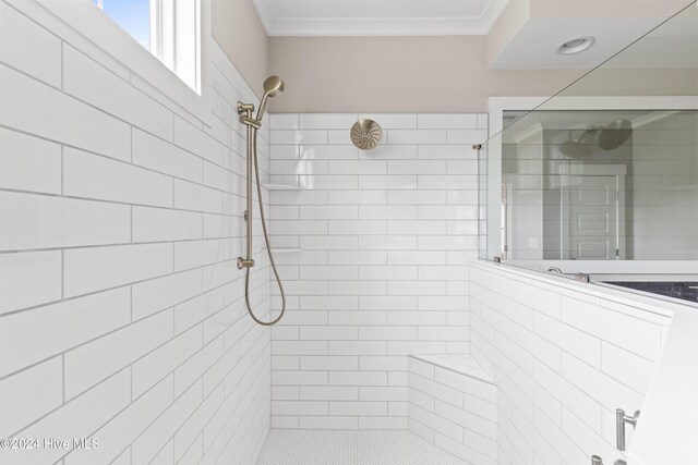 bathroom with a tile shower and crown molding