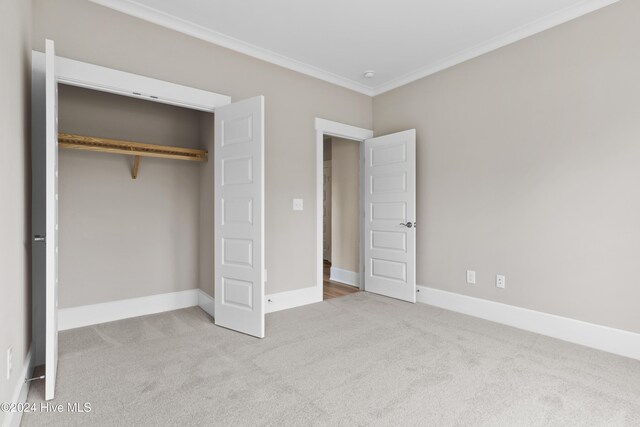 unfurnished bedroom with light carpet, a closet, and ornamental molding