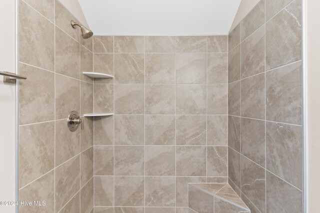 bathroom with a tile shower and vaulted ceiling