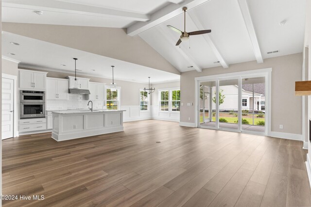 unfurnished living room with beamed ceiling, dark wood-type flooring, ceiling fan with notable chandelier, and high vaulted ceiling