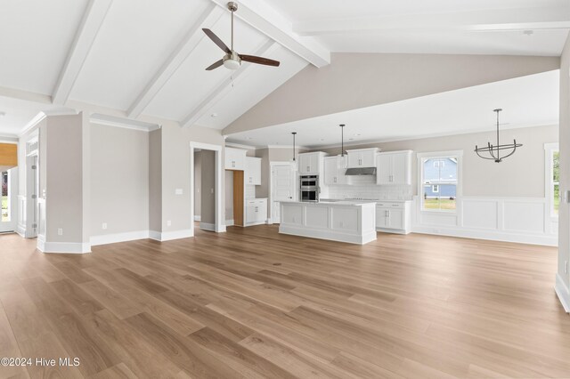 unfurnished living room with beam ceiling, ceiling fan with notable chandelier, high vaulted ceiling, and light hardwood / wood-style flooring