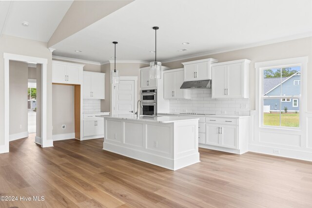 kitchen featuring backsplash, double oven, a center island with sink, light hardwood / wood-style floors, and white cabinetry