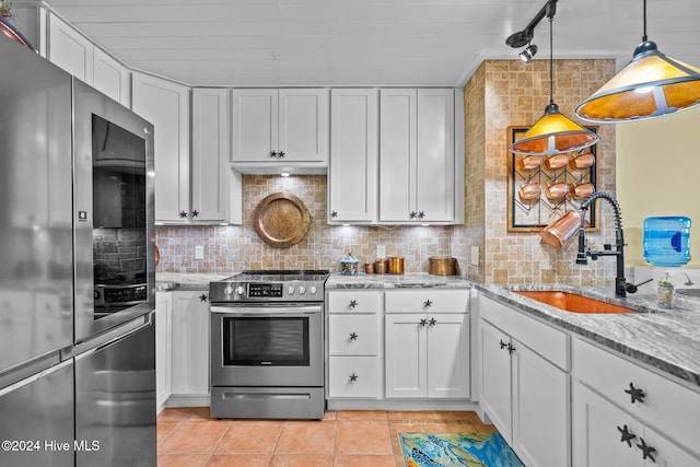 kitchen with hanging light fixtures, sink, decorative backsplash, appliances with stainless steel finishes, and white cabinetry