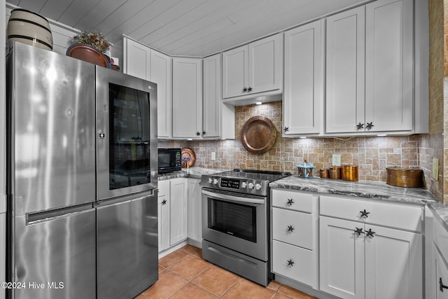 kitchen featuring light stone countertops, appliances with stainless steel finishes, tasteful backsplash, light tile patterned floors, and white cabinetry