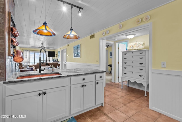 kitchen featuring white cabinetry, ceiling fan, dark stone countertops, pendant lighting, and light tile patterned floors