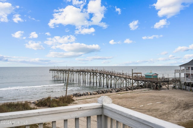 view of dock featuring a water view and a beach view