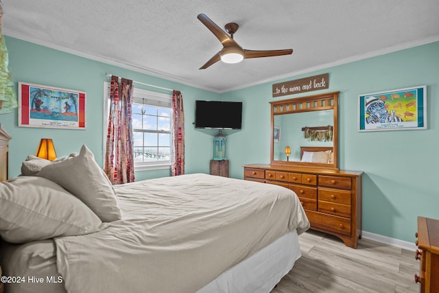 bedroom featuring ceiling fan, light hardwood / wood-style flooring, a textured ceiling, and ornamental molding