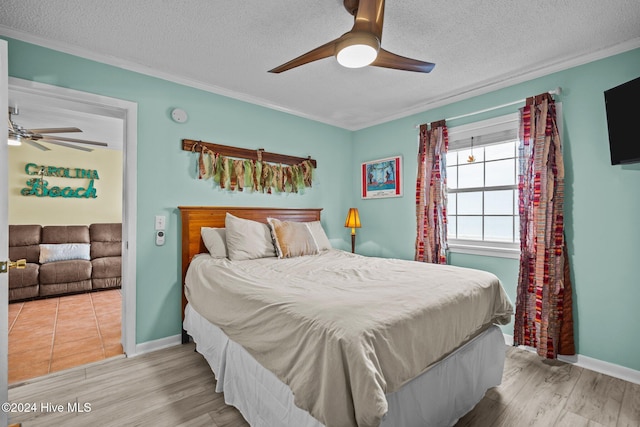 bedroom featuring ceiling fan, crown molding, light wood-type flooring, and a textured ceiling