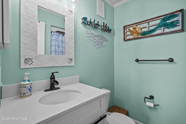 bathroom featuring toilet, vanity, and ornamental molding