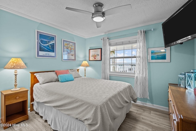 bedroom with ceiling fan, light hardwood / wood-style floors, ornamental molding, and a textured ceiling