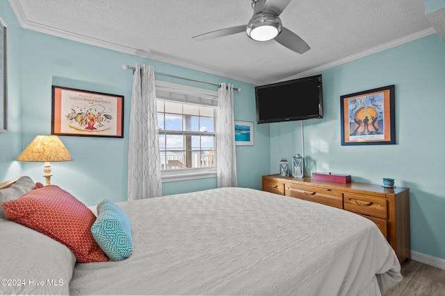 bedroom with wood-type flooring, a textured ceiling, ceiling fan, and ornamental molding