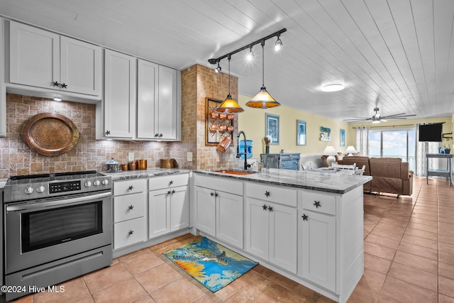 kitchen featuring white cabinets, sink, stainless steel stove, and hanging light fixtures