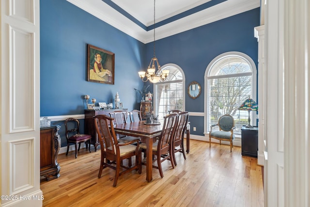 dining space featuring an inviting chandelier, ornamental molding, and light hardwood / wood-style floors