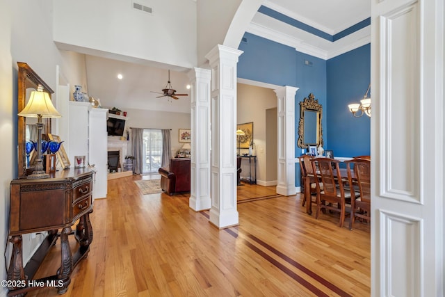 entryway featuring decorative columns, ceiling fan, light wood-type flooring, a towering ceiling, and ornamental molding