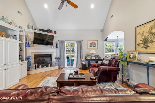 living room with a wealth of natural light, a tile fireplace, and high vaulted ceiling