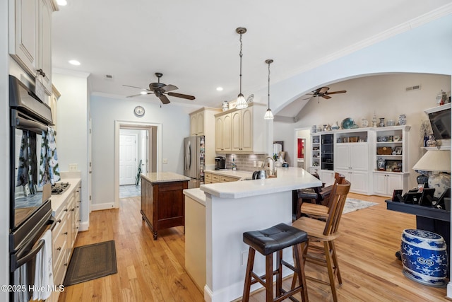 kitchen with kitchen peninsula, stainless steel appliances, backsplash, hanging light fixtures, and crown molding