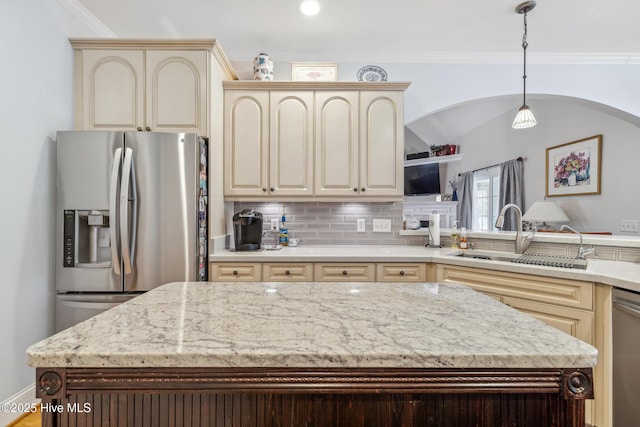 kitchen with tasteful backsplash, sink, hanging light fixtures, appliances with stainless steel finishes, and cream cabinetry