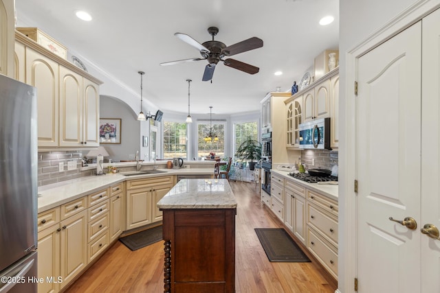 kitchen featuring backsplash, a kitchen island, sink, hanging light fixtures, and stainless steel appliances