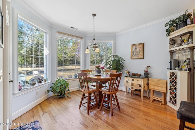 dining space with crown molding, a chandelier, and light wood-type flooring