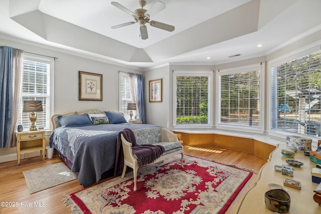 bedroom featuring ceiling fan, a tray ceiling, and multiple windows