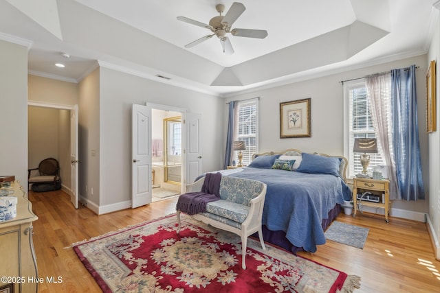 bedroom featuring hardwood / wood-style flooring, ceiling fan, ensuite bathroom, and a raised ceiling