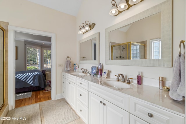 bathroom featuring a shower with shower door, tile patterned floors, vanity, and vaulted ceiling