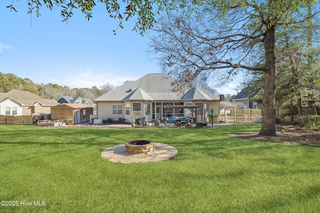 rear view of house featuring a lawn, an outdoor fire pit, and a sunroom