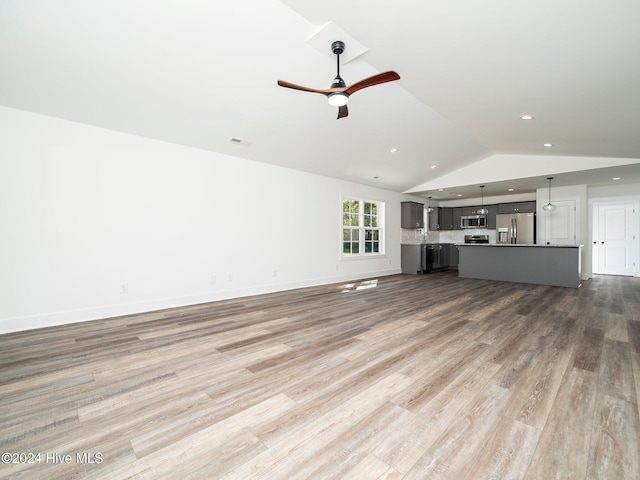 unfurnished living room with hardwood / wood-style floors, vaulted ceiling, and ceiling fan