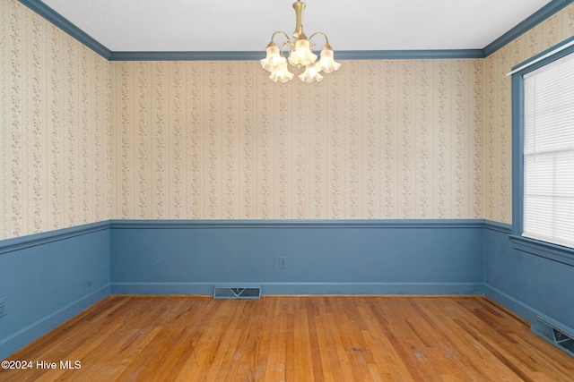 unfurnished room featuring a wealth of natural light, wood-type flooring, and crown molding