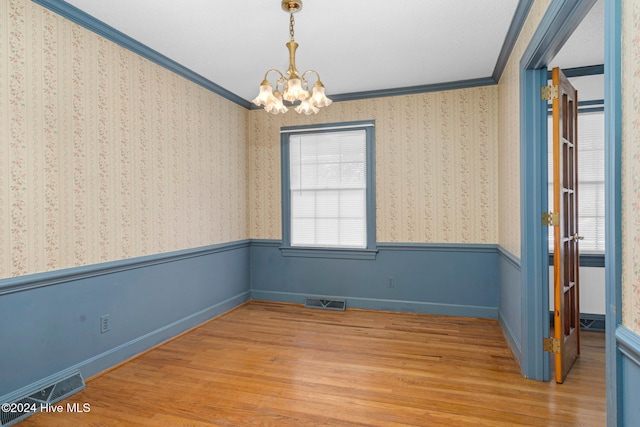 unfurnished room featuring light hardwood / wood-style floors, a chandelier, and crown molding