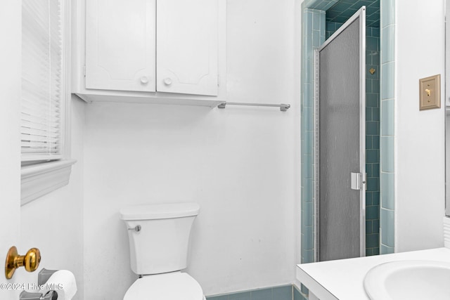 bathroom featuring vanity, toilet, and a shower with shower door