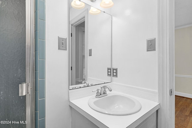 bathroom with wood-type flooring, vanity, and crown molding