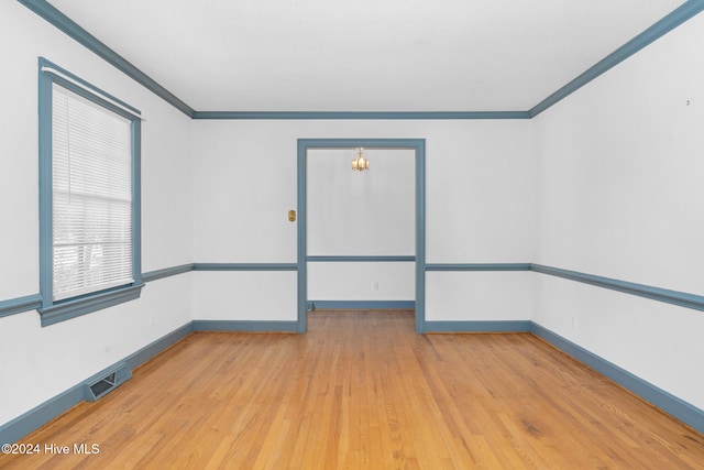 empty room with light hardwood / wood-style floors and crown molding