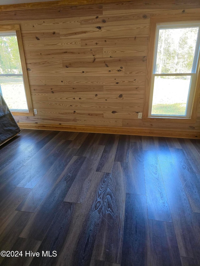 empty room with dark hardwood / wood-style flooring and wooden walls