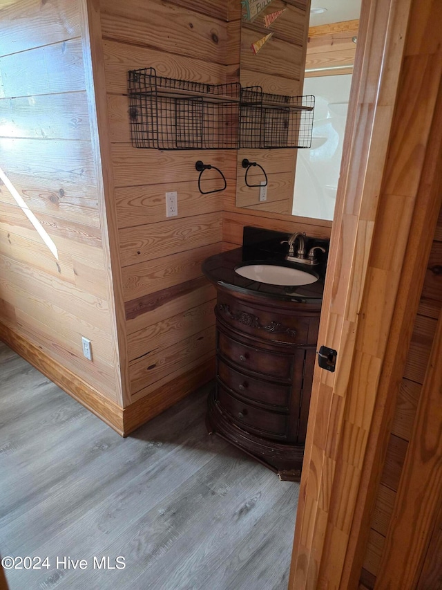 bathroom featuring vanity, wooden walls, and hardwood / wood-style flooring