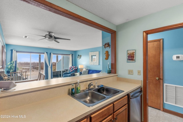 kitchen featuring a textured ceiling, light carpet, sink, stainless steel dishwasher, and ceiling fan