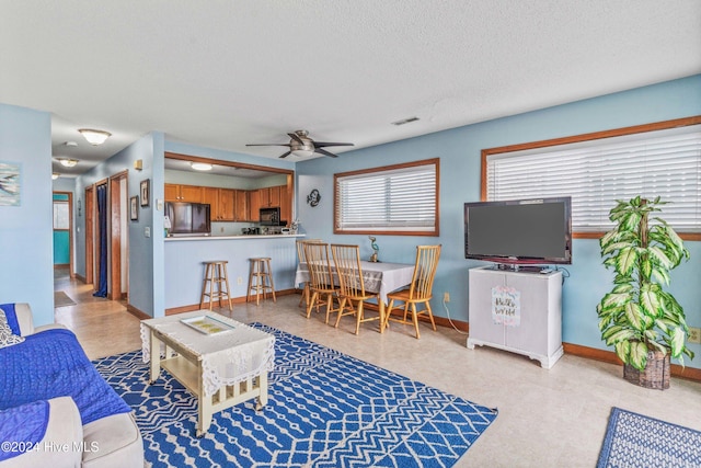 living room with a textured ceiling and ceiling fan