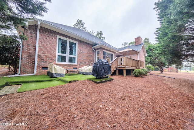 rear view of property featuring a yard and a wooden deck